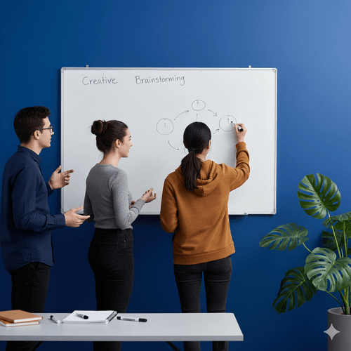 Three students at a whiteboard headed &ldquo;Creative Brainstorming&rdquo;, one of them drawing a diagram of linked circles while the others talk it through.
